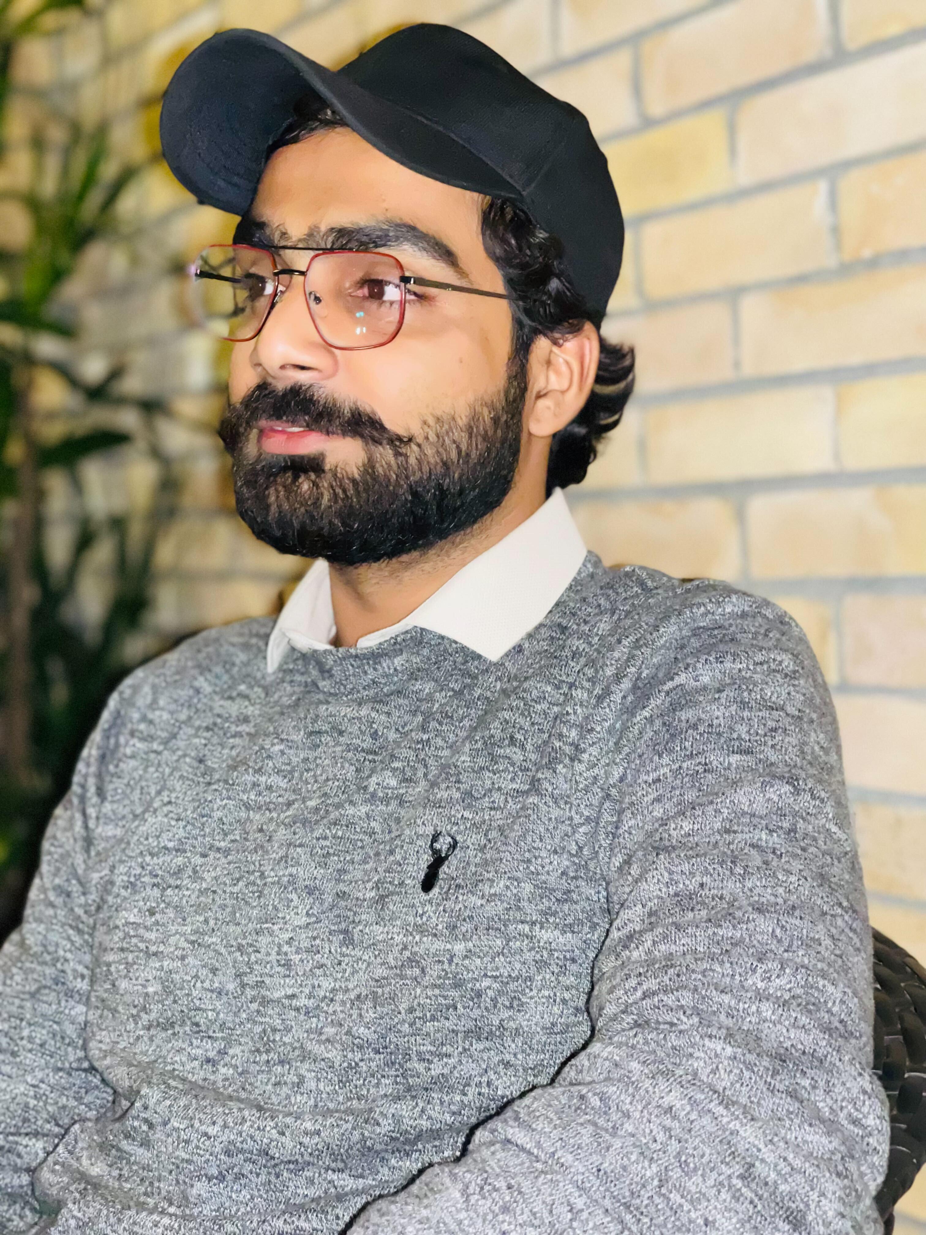 Azeem Shafeeq wearing glasses, a black cap and a grey sweater